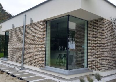 Dom jednorodzinny – stolarka aluminiowa – okna narożne bez słupka, szklany daszek nad wejściem, aluminiowe okna przesuwne